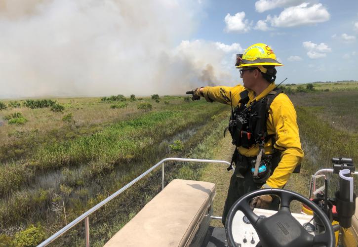 Park Services Specialist Chris Camargo pointing at the prescribed fire smoke in the distance